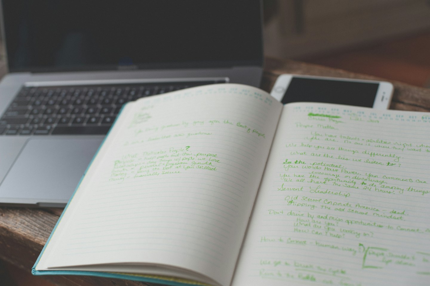 Notebook with green ink notes on a wooden desk.
